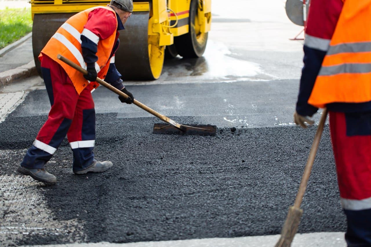 Worker sealing cracks in fresh asphalt
